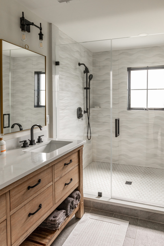 This is an example of a mid-sized country bathroom in New York with light wood cabinets, an alcove shower, gray tile, ceramic tile, white walls, ceramic floors, an undermount sink, engineered quartz benchtops, grey floor, a hinged shower door, white benchtops, a double vanity, a freestanding vanity and flat-panel cabinets.