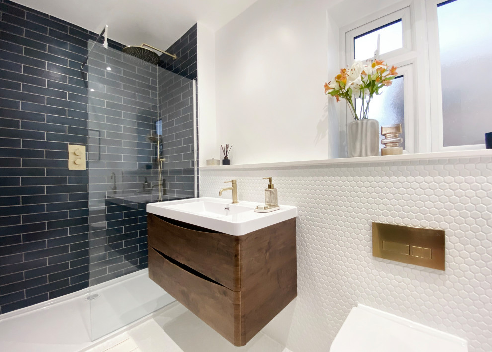 Photo of a medium sized contemporary grey and white ensuite half tiled bathroom in Kent with flat-panel cabinets, dark wood cabinets, a walk-in shower, all types of toilet, white tiles, porcelain tiles, white walls, porcelain flooring, a built-in sink, engineered stone worktops, grey floors, an open shower, blue worktops, a single sink, a floating vanity unit and all types of ceiling.