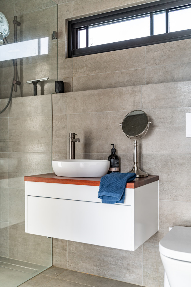 This is an example of a contemporary bathroom in Perth with flat-panel cabinets, white cabinets, an alcove shower, gray tile, a vessel sink, wood benchtops, grey floor, brown benchtops, a single vanity and a floating vanity.