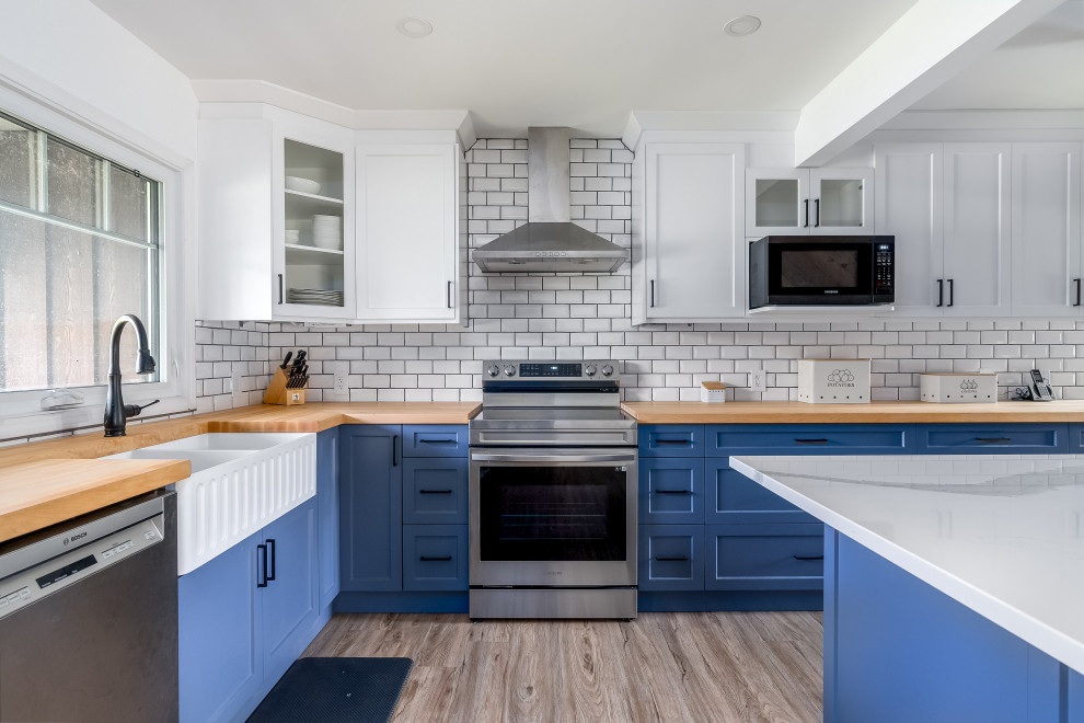 Inspiration for a transitional kitchen remodel in Edmonton with shaker cabinets, blue cabinets, quartzite countertops, subway tile backsplash, stainless steel appliances, an island and white countertops