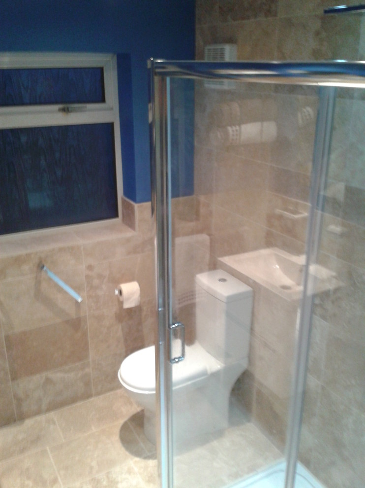 Photo of a small contemporary master bathroom in West Midlands with a wall-mount sink, flat-panel cabinets, white cabinets, solid surface benchtops, a double shower, a two-piece toilet, beige tile, stone tile, blue walls and travertine floors.