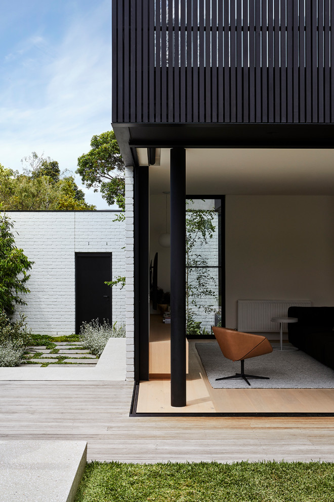 Photo of a mid-sized modern two-storey black house exterior in Melbourne with wood siding and a metal roof.