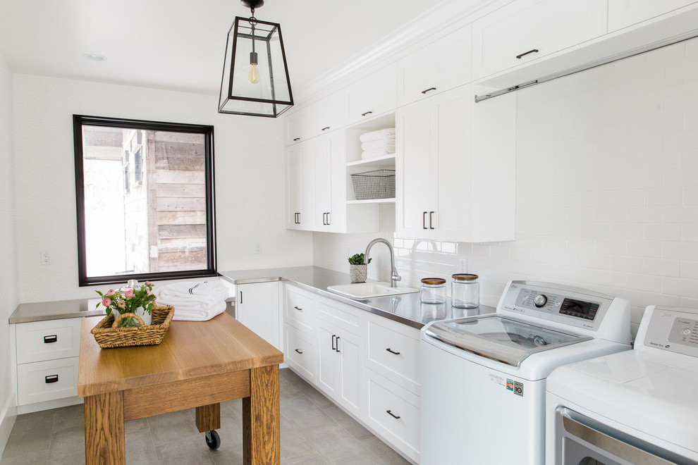 Transitional laundry room in Salt Lake City with a drop-in sink, white cabinets, stainless steel benchtops, white walls and shaker cabinets.