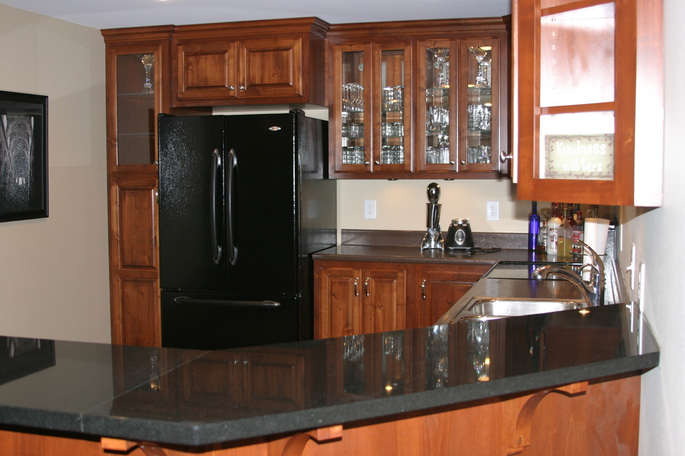 Open concept kitchen - small u-shaped open concept kitchen idea with raised-panel cabinets, dark wood cabinets, black appliances and a peninsula