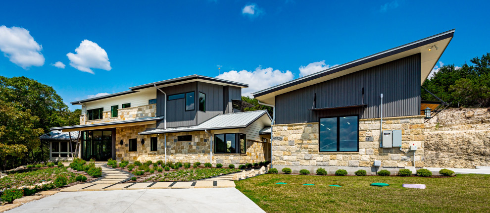 Example of a transitional two-story house exterior design in Austin with a hip roof and a metal roof