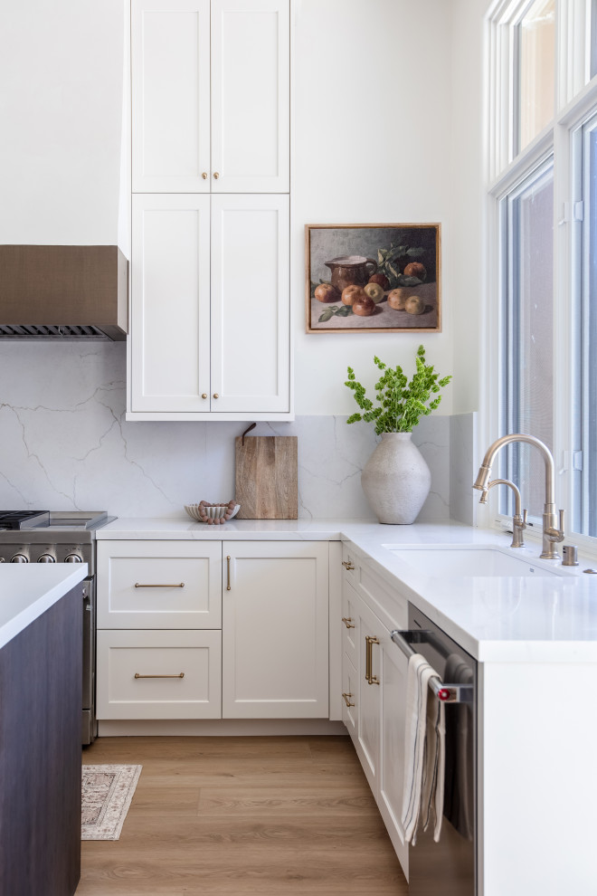 Example of a large l-shaped vinyl floor and brown floor kitchen design in San Diego with an undermount sink, shaker cabinets, quartz countertops, quartz backsplash, stainless steel appliances, an island and white countertops