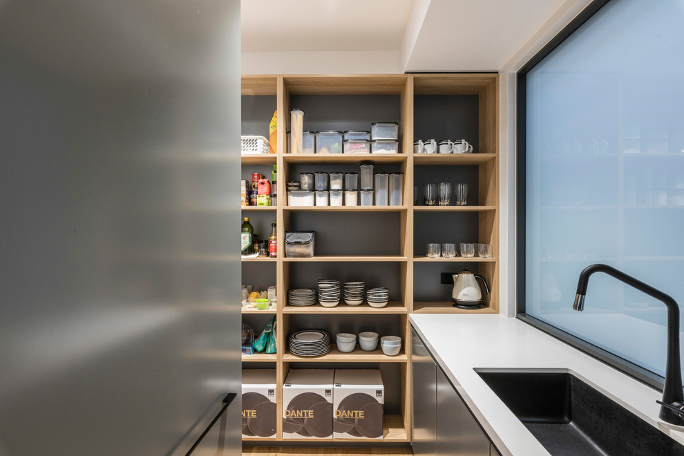 Design ideas for a mid-sized modern galley kitchen pantry in Brisbane with an undermount sink, open cabinets, grey cabinets, marble benchtops, yellow splashback, marble splashback, black appliances, light hardwood floors, with island, beige floor and white benchtop.
