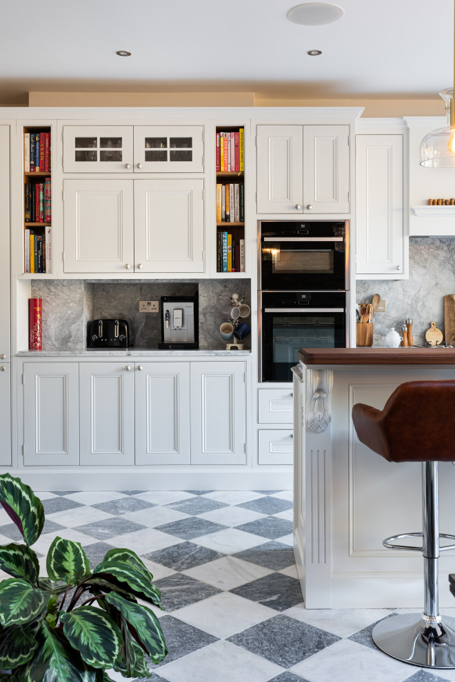 Eat-in kitchen - mid-sized victorian single-wall eat-in kitchen idea in London with shaker cabinets, white cabinets, quartzite countertops, gray backsplash, granite backsplash, stainless steel appliances, an island and gray countertops