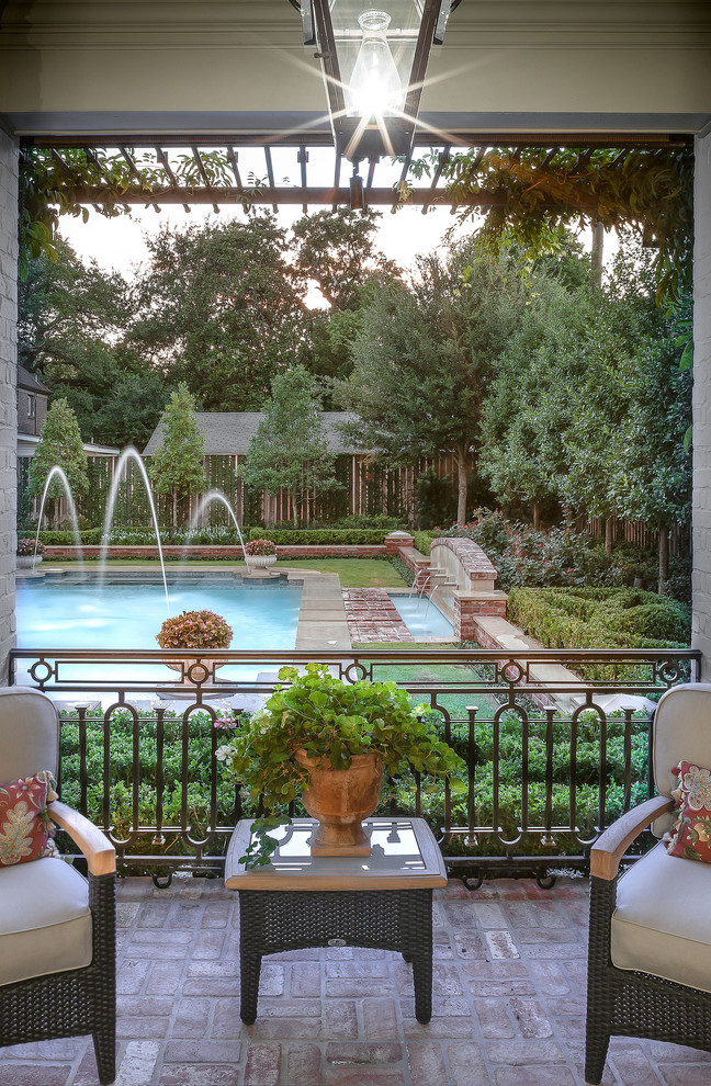 Inspiration for a large traditional backyard pool in Houston with brick pavers.