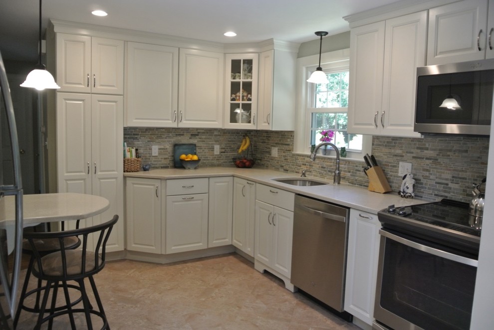 Inspiration for a transitional u-shaped porcelain tile and beige floor kitchen remodel in Boston with an undermount sink, raised-panel cabinets, white cabinets, beige backsplash, subway tile backsplash and stainless steel appliances