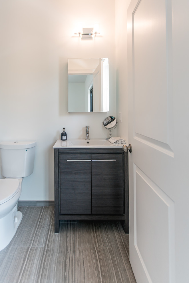 Photo of a small modern bathroom in New York with flat-panel cabinets, grey cabinets, a one-piece toilet, white tile, white walls, porcelain floors, laminate benchtops and grey floor.