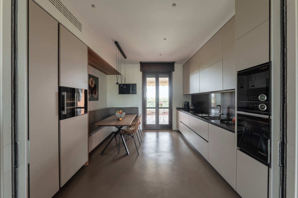 This is an example of a large modern galley separate kitchen in Milan with a double-bowl sink, flat-panel cabinets, beige cabinets, solid surface benchtops, brown splashback, porcelain splashback, black appliances, dark hardwood floors, no island, brown floor, brown benchtop and recessed.