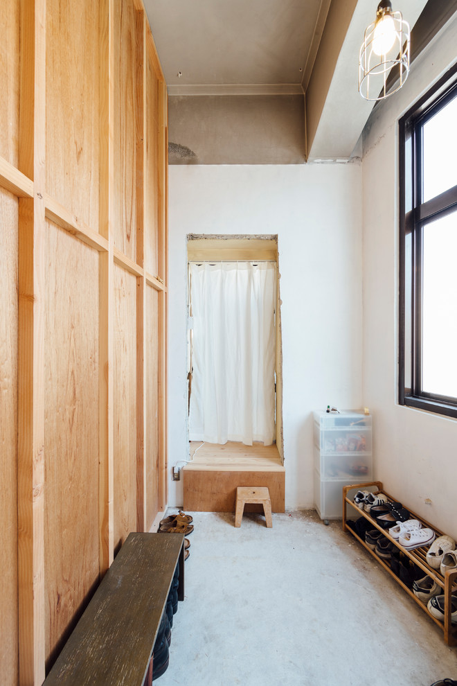 This is an example of an industrial mudroom in Other with white walls and concrete floors.