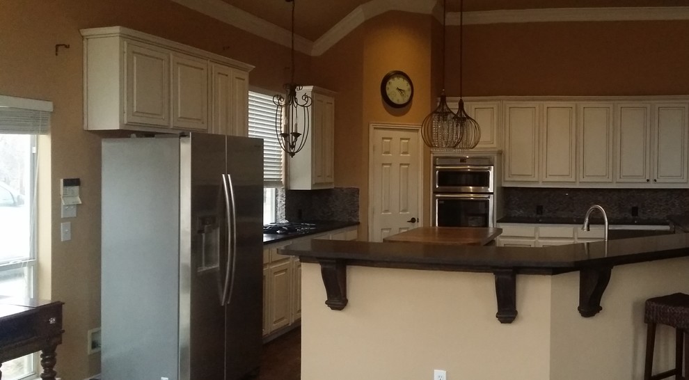 Large transitional brown floor open concept kitchen photo in Dallas with an undermount sink, raised-panel cabinets, white cabinets, granite countertops, gray backsplash, stone tile backsplash, stainless steel appliances and an island