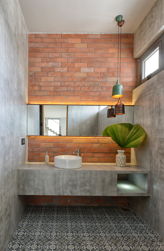 Photo of an industrial bathroom in Ahmedabad With Gray Tile, Cement Tile, Grey Walls, Ceramic Floors, a Vessel Sink and Concrete Benchtops.