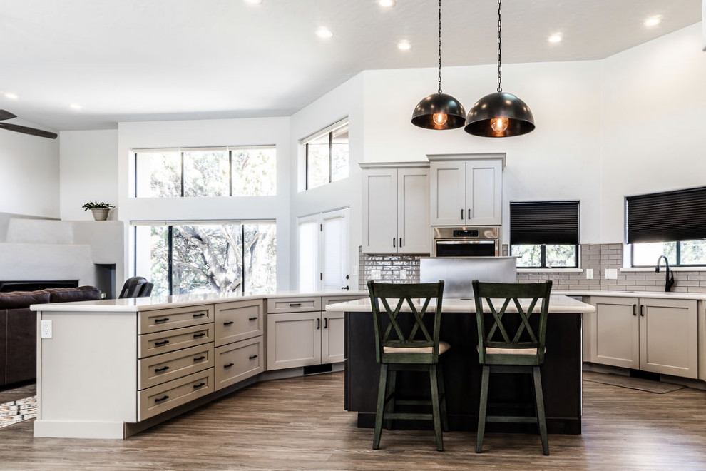 Example of a large transitional u-shaped vinyl floor and gray floor eat-in kitchen design with an undermount sink, shaker cabinets, gray cabinets, quartzite countertops, green backsplash, subway tile backsplash, stainless steel appliances, an island and white countertops