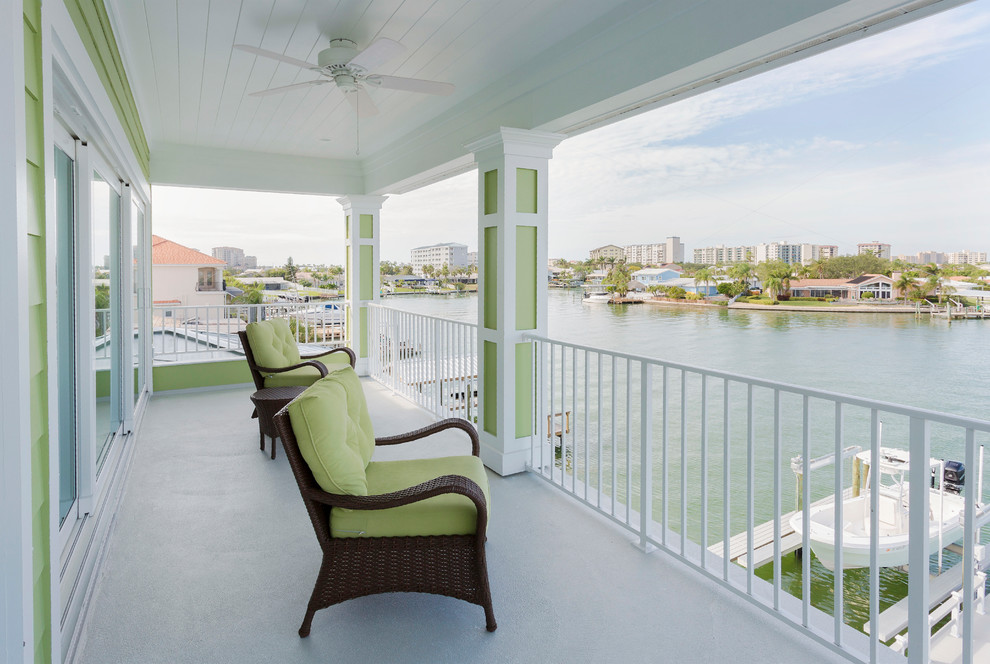 Design ideas for a mid-sized beach style balcony in Tampa with a roof extension and metal railing.