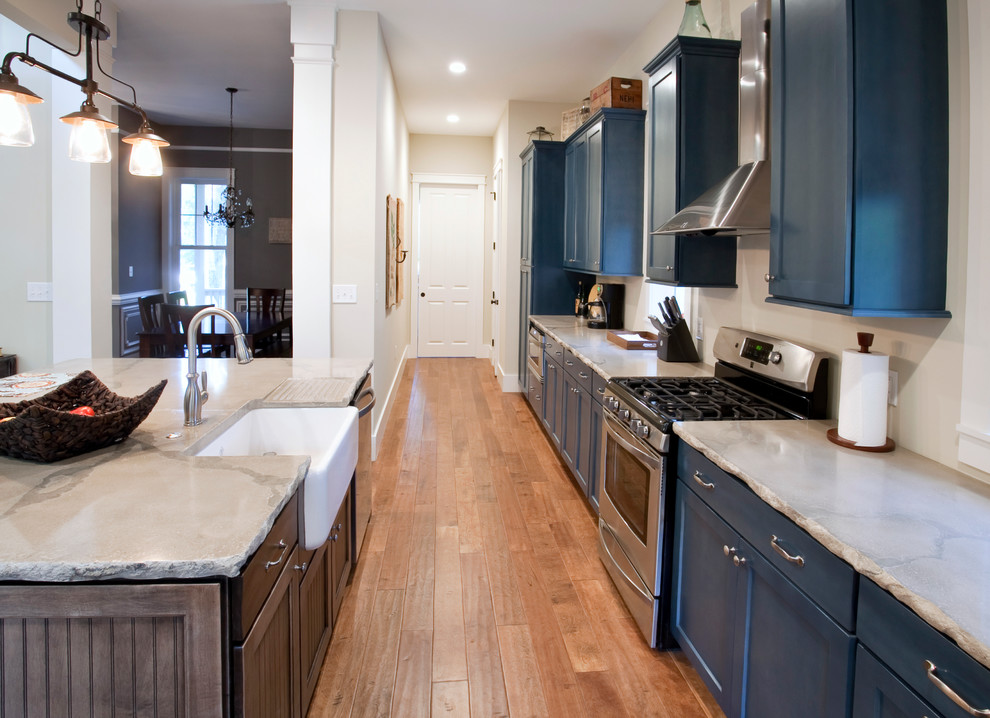 This is an example of a traditional galley kitchen in Charleston with blue cabinets, concrete benchtops, a farmhouse sink, shaker cabinets and stainless steel appliances.