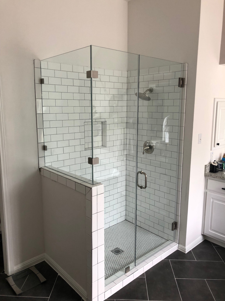 Contemporary master bathroom in Austin with a corner shower, white tile, subway tile, beige walls, black floor and a hinged shower door.