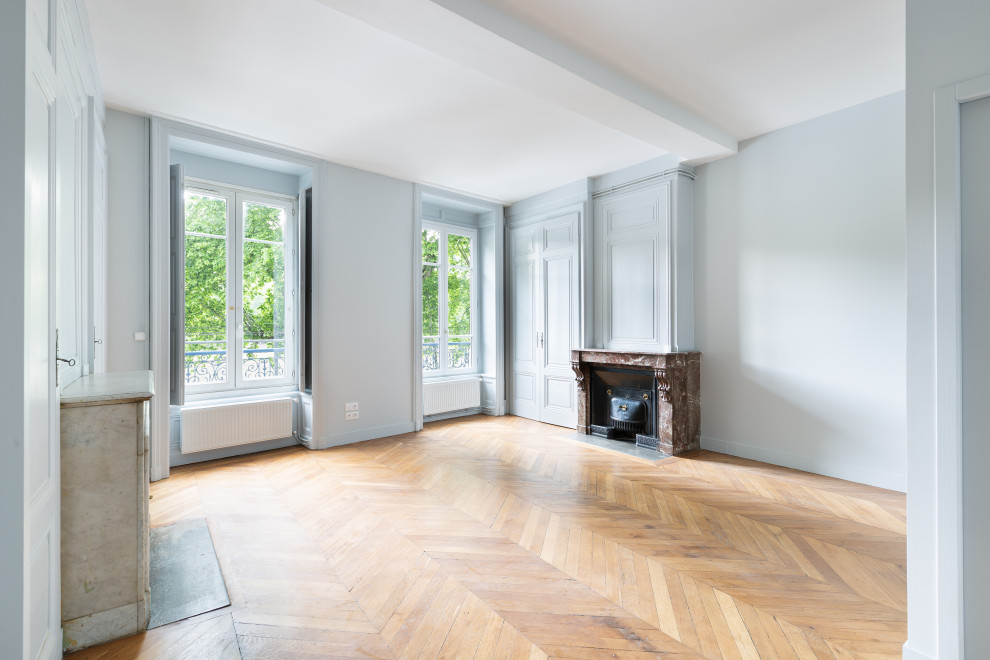 Inredning av ett klassiskt mellanstort separat vardagsrum, med blå väggar, ljust trägolv, en standard öppen spis och brunt golv