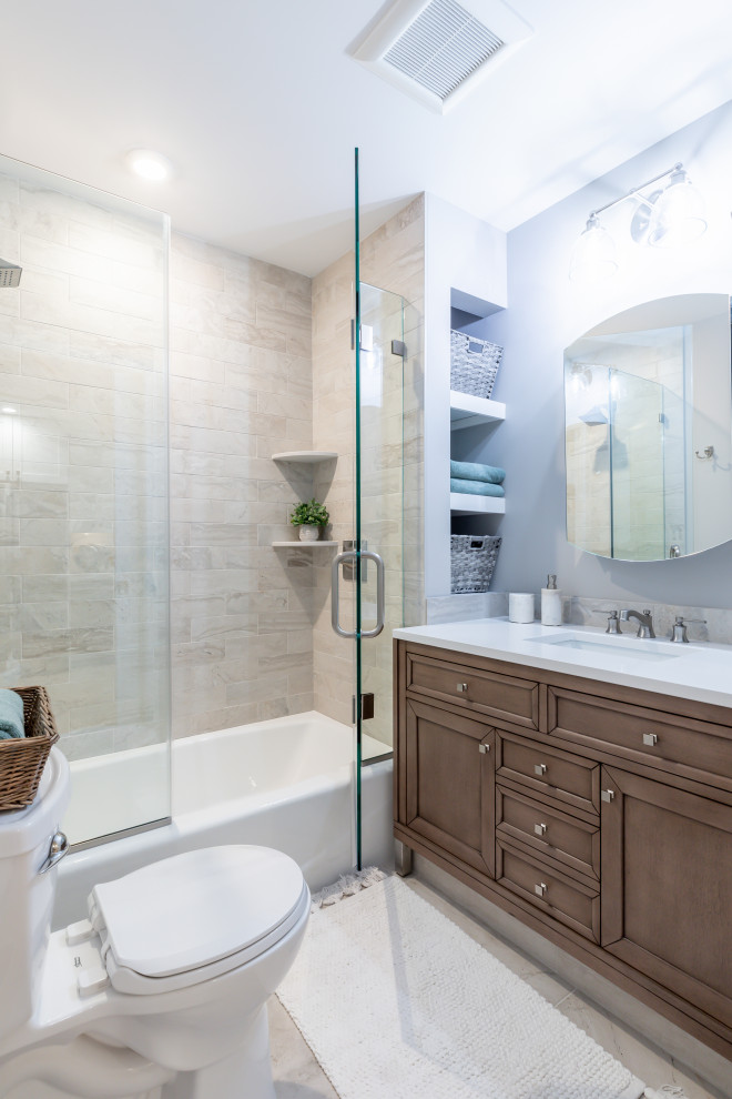 Inspiration for a mid-sized transitional bathroom in Philadelphia with shaker cabinets, brown cabinets, gray tile, ceramic floors, engineered quartz benchtops, white floor, a hinged shower door, white benchtops and an alcove shower.