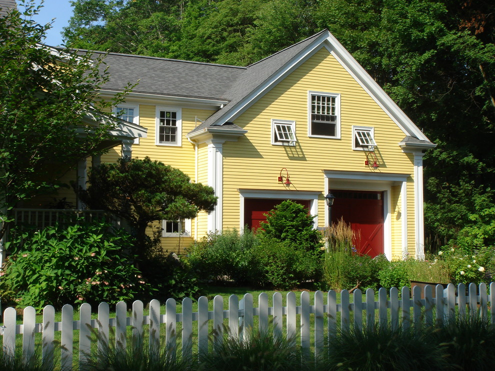 Country two-storey yellow exterior in Boston with wood siding.