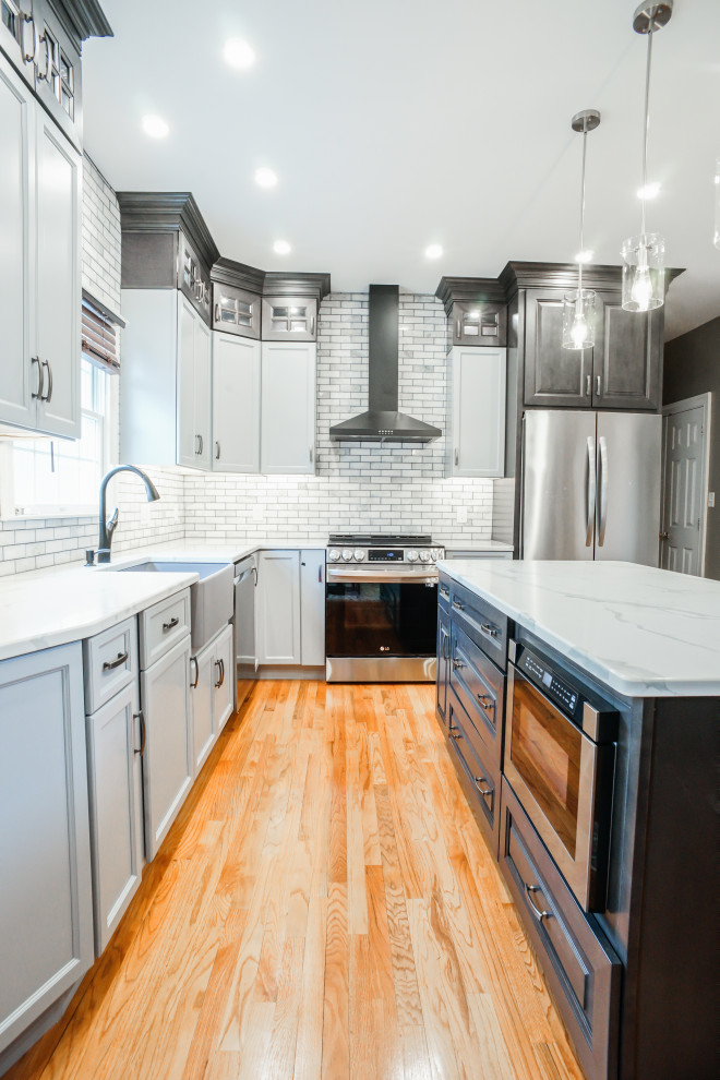 Klassische Küche mit profilierten Schrankfronten, grauen Schränken, Quarzwerkstein-Arbeitsplatte, Rückwand aus Mosaikfliesen, hellem Holzboden, Kücheninsel, orangem Boden und weißer Arbeitsplatte in Philadelphia