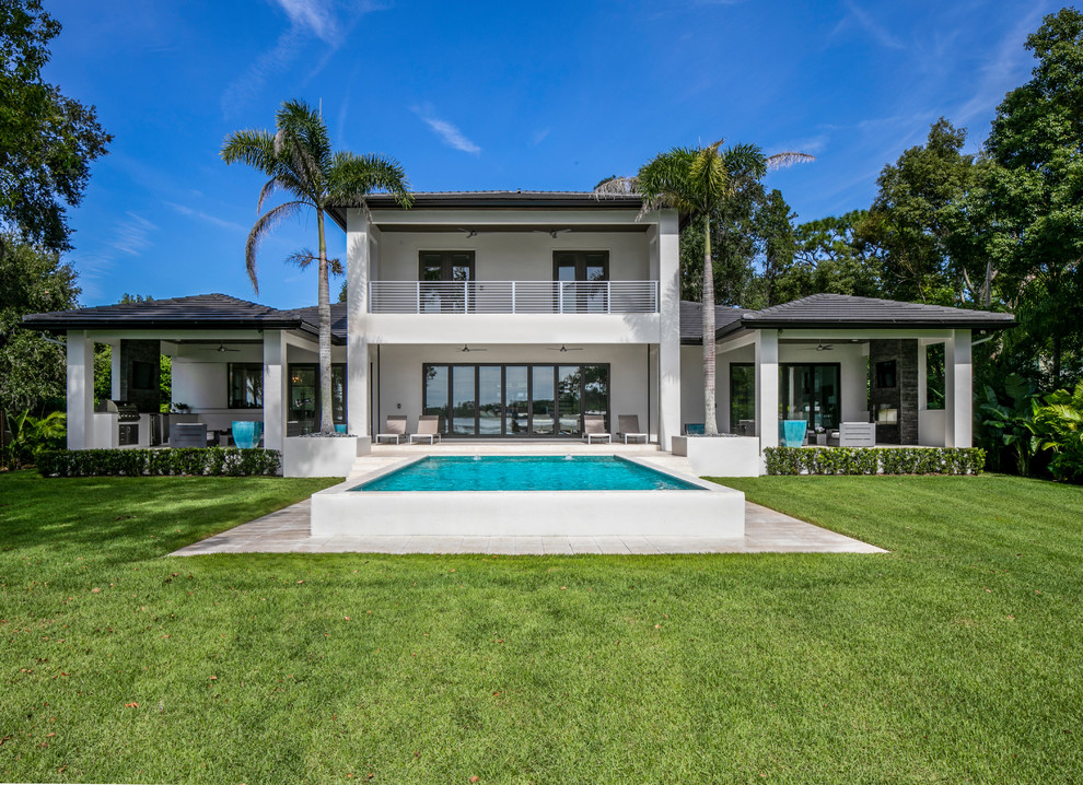 Photo of an expansive modern two-storey stucco white house exterior in Tampa with a hip roof and a shingle roof.