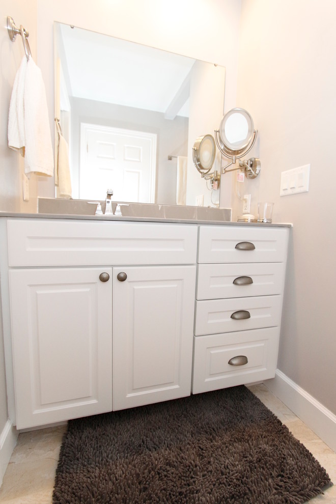 Photo of a mid-sized transitional master bathroom in Grand Rapids with an integrated sink, raised-panel cabinets, white cabinets, solid surface benchtops, an alcove tub, an alcove shower, a two-piece toilet, multi-coloured tile, porcelain tile, grey walls and porcelain floors.