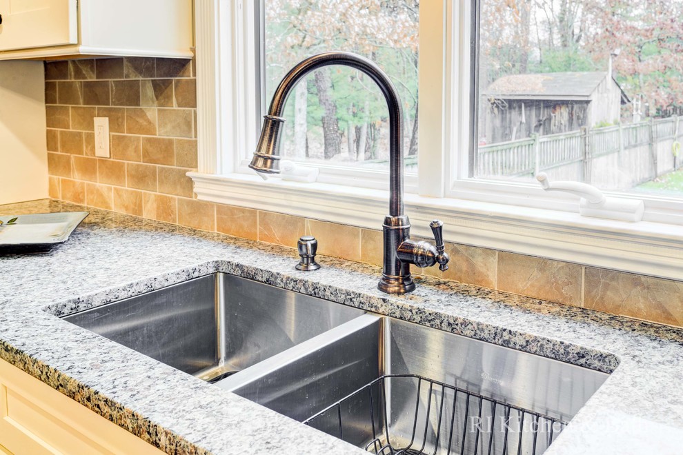 Example of a large transitional u-shaped light wood floor eat-in kitchen design in Providence with an undermount sink, shaker cabinets, beige cabinets, granite countertops, brown backsplash, porcelain backsplash, stainless steel appliances and an island
