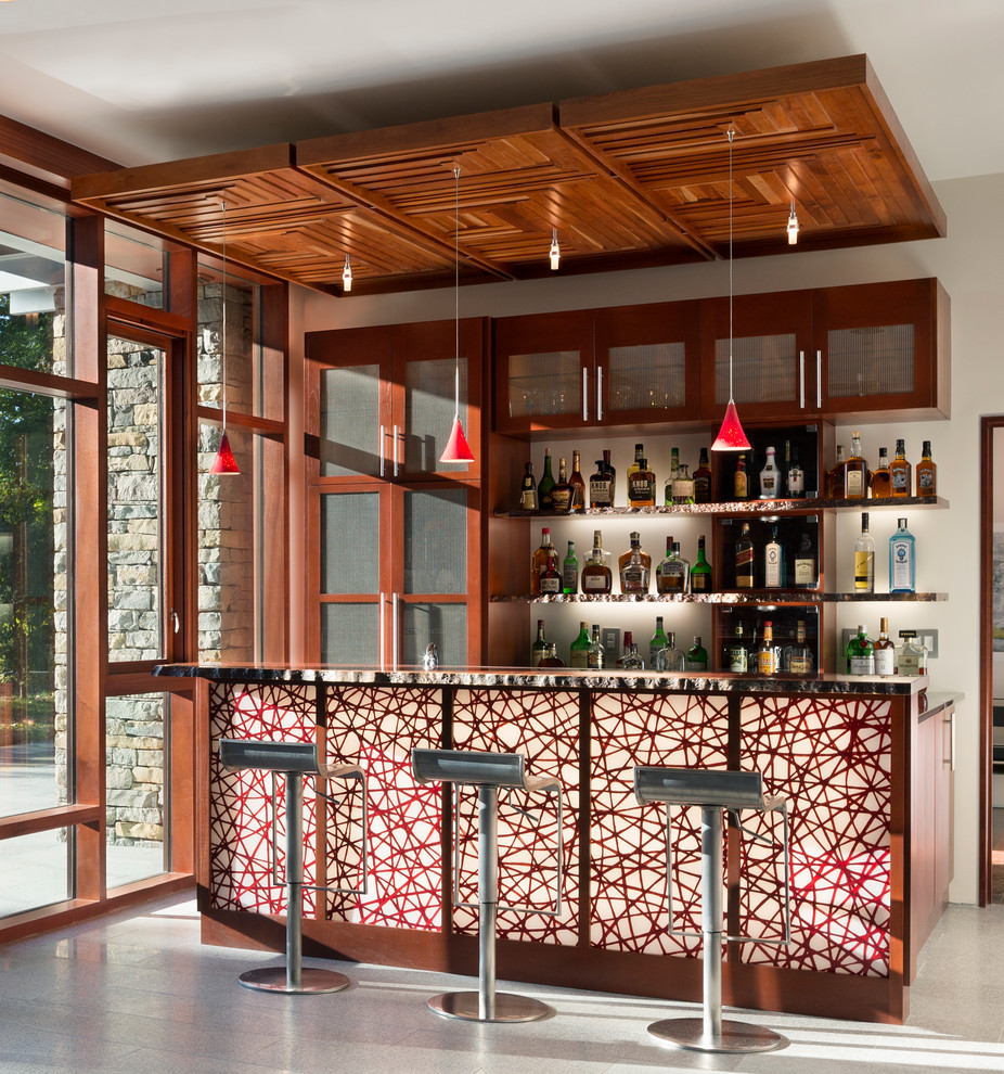 Inspiration for a contemporary single-wall seated home bar in New Orleans with glass-front cabinets, medium wood cabinets and concrete floors.