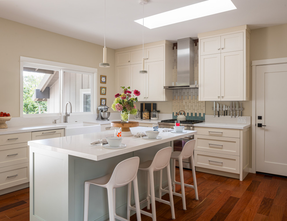 Photo of a midcentury kitchen in San Francisco with a farmhouse sink, shaker cabinets, blue cabinets, quartz benchtops, beige splashback, engineered quartz splashback and medium hardwood floors.