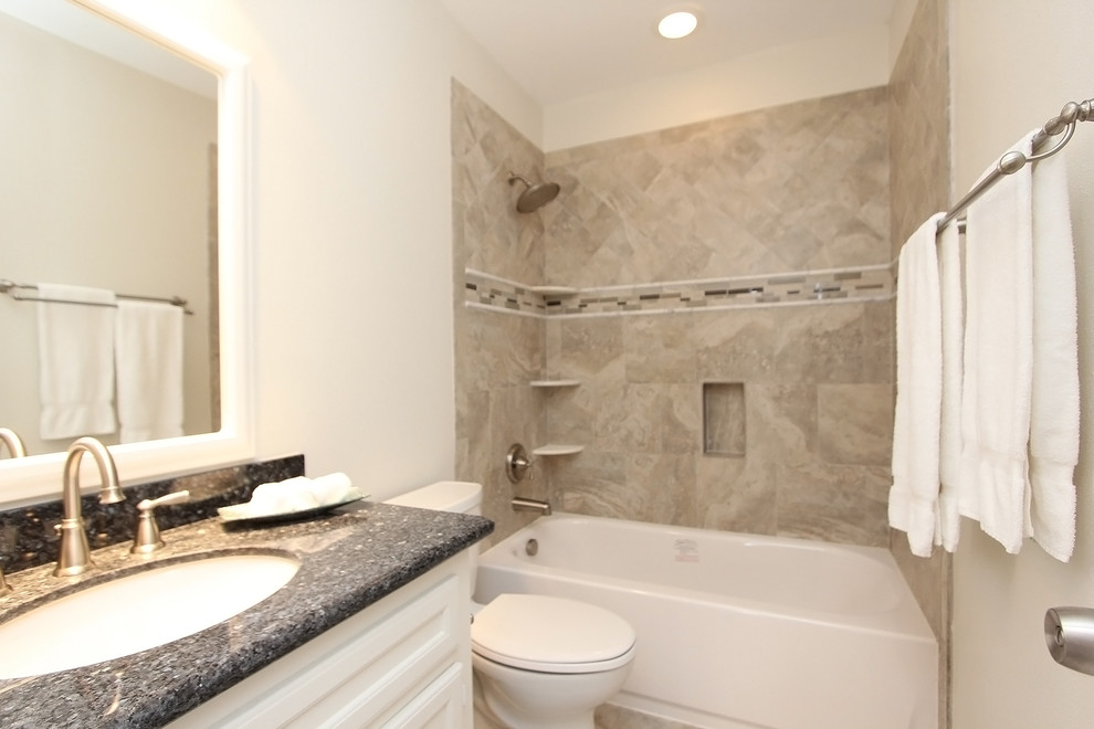 Mid-sized arts and crafts kids bathroom in Houston with recessed-panel cabinets, white cabinets, an alcove tub, a shower/bathtub combo, a two-piece toilet, beige tile, ceramic tile, white walls, an undermount sink and granite benchtops.