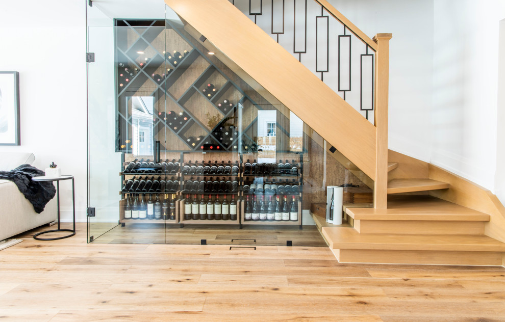 This is an example of a transitional wine cellar in Toronto with light hardwood floors, diamond bins and beige floor.
