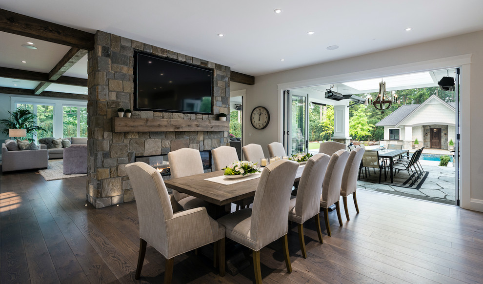 Mid-sized transitional kitchen/dining combo with a stone fireplace surround, grey walls, dark hardwood floors, brown floor and a two-sided fireplace.