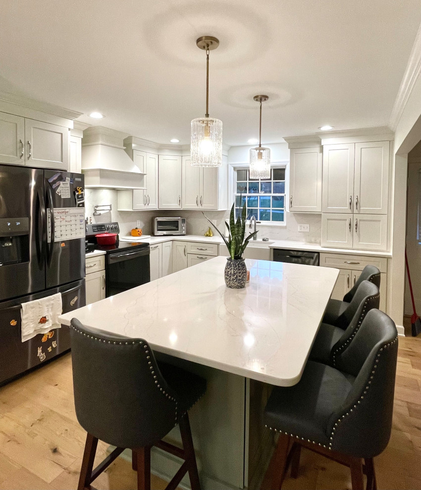 Inspiration for a transitional l-shaped light wood floor and beige floor eat-in kitchen remodel with a farmhouse sink, shaker cabinets, white cabinets, quartz countertops, white backsplash, quartz backsplash, black appliances, an island and white countertops