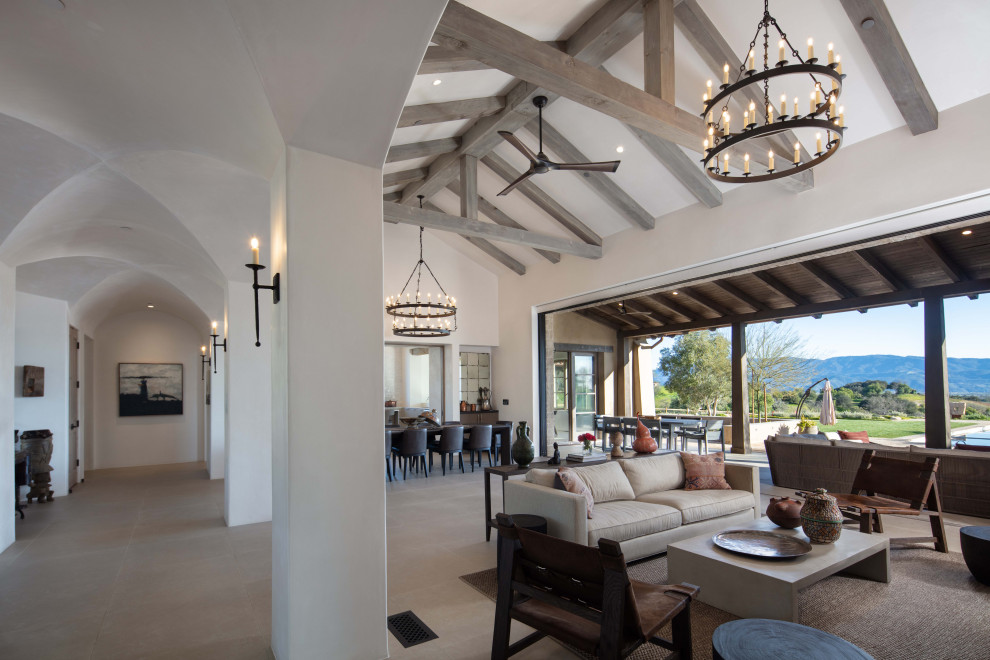 Mediterranes Wohnzimmer mit gelber Wandfarbe, hellem Holzboden, braunem Boden und freigelegten Dachbalken in Santa Barbara