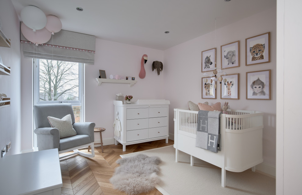 Photo of a mid-sized transitional nursery for girls in Other with pink walls, medium hardwood floors and brown floor.
