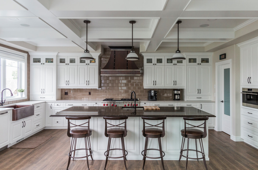 Exempel på ett stort klassiskt flerfärgad flerfärgat kök, med en rustik diskho, luckor med upphöjd panel, vita skåp, bänkskiva i kvarts, beige stänkskydd, stänkskydd i tunnelbanekakel, rostfria vitvaror, klinkergolv i keramik, en köksö och brunt golv