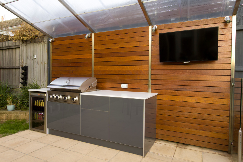 Photo of a contemporary backyard patio in Melbourne with an outdoor kitchen, concrete pavers and an awning.