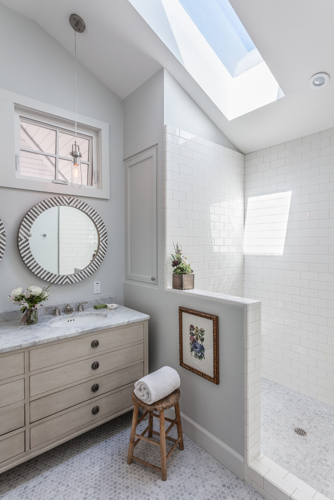 Inspiration for a beach style bathroom in San Francisco with an undermount sink, flat-panel cabinets, light wood cabinets, white tile, subway tile, grey walls and mosaic tile floors.