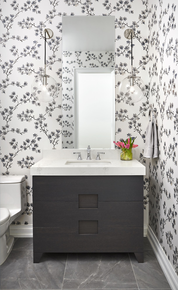 Inspiration for a mid-sized contemporary powder room in Toronto with black cabinets, a one-piece toilet, multi-coloured walls, porcelain floors, an undermount sink, engineered quartz benchtops, grey floor, white benchtops and furniture-like cabinets.