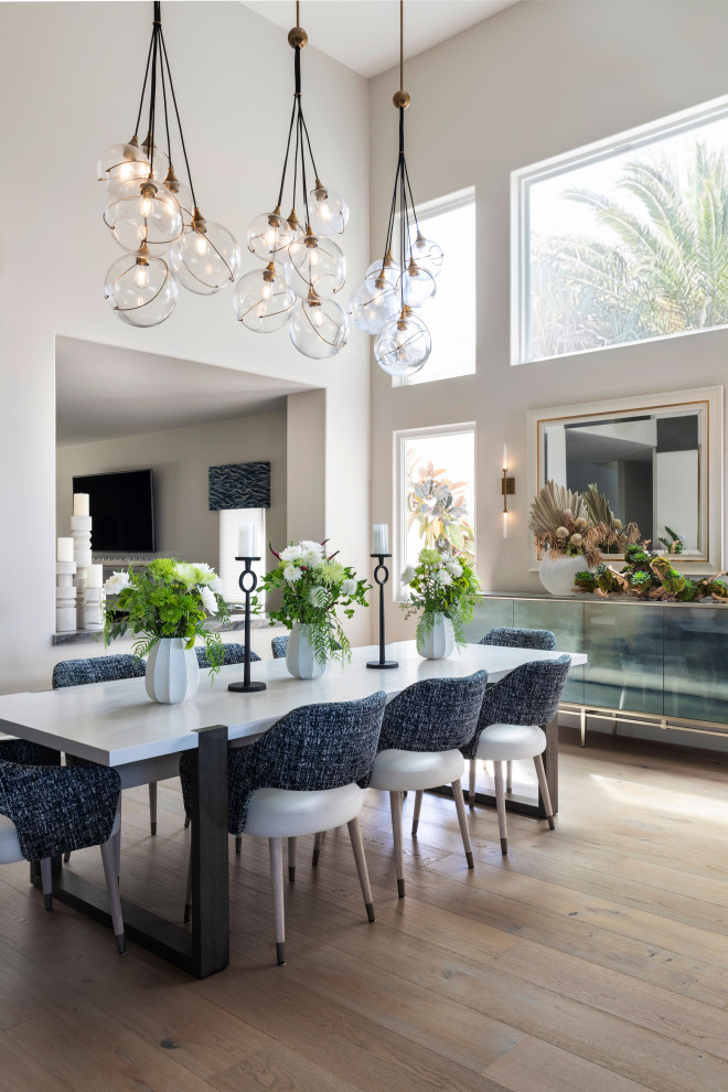 This is an example of a large modern open plan dining room in Orange County with white walls, light hardwood flooring, grey floors and a vaulted ceiling.
