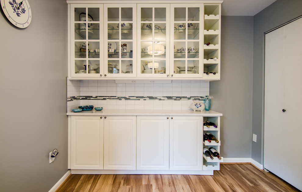 Example of a mid-sized transitional l-shaped vinyl floor enclosed kitchen design in DC Metro with an undermount sink, shaker cabinets, quartz countertops, white backsplash, ceramic backsplash, black appliances and no island