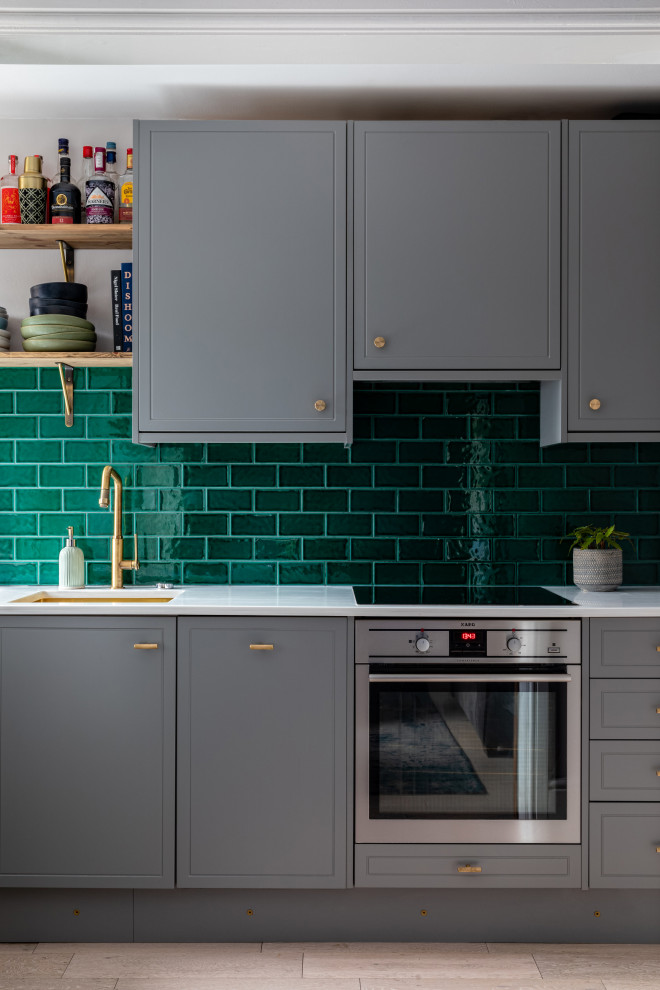 Foto på ett litet eklektiskt vit kök, med en enkel diskho, luckor med profilerade fronter, grå skåp, bänkskiva i koppar, grönt stänkskydd, stänkskydd i keramik, svarta vitvaror, ljust trägolv och grått golv