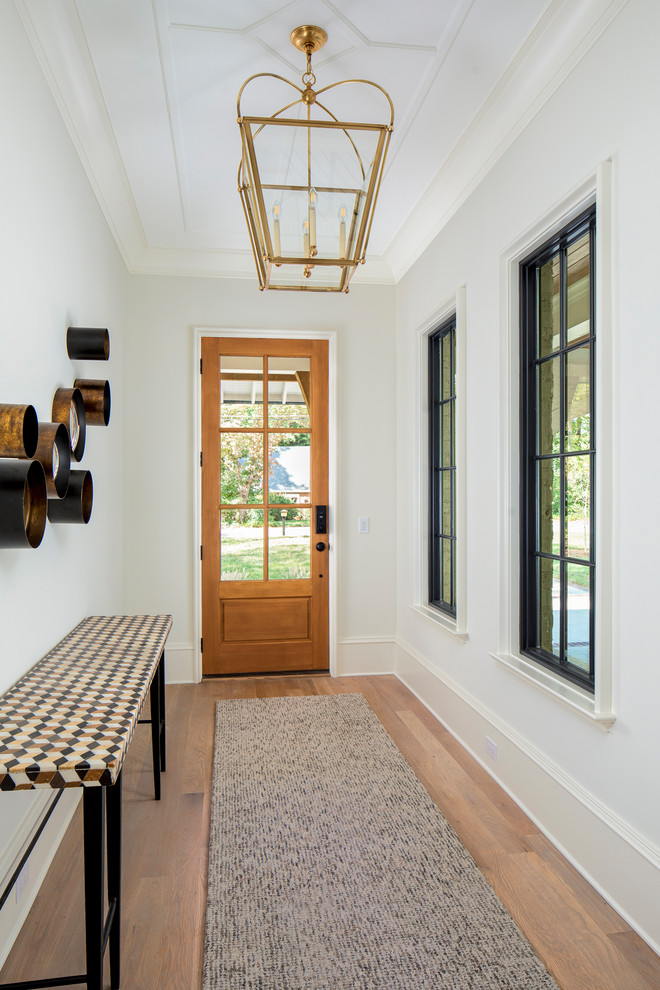 Photo of a large transitional front door in Charlotte with white walls, medium hardwood floors, a single front door, a medium wood front door and brown floor.