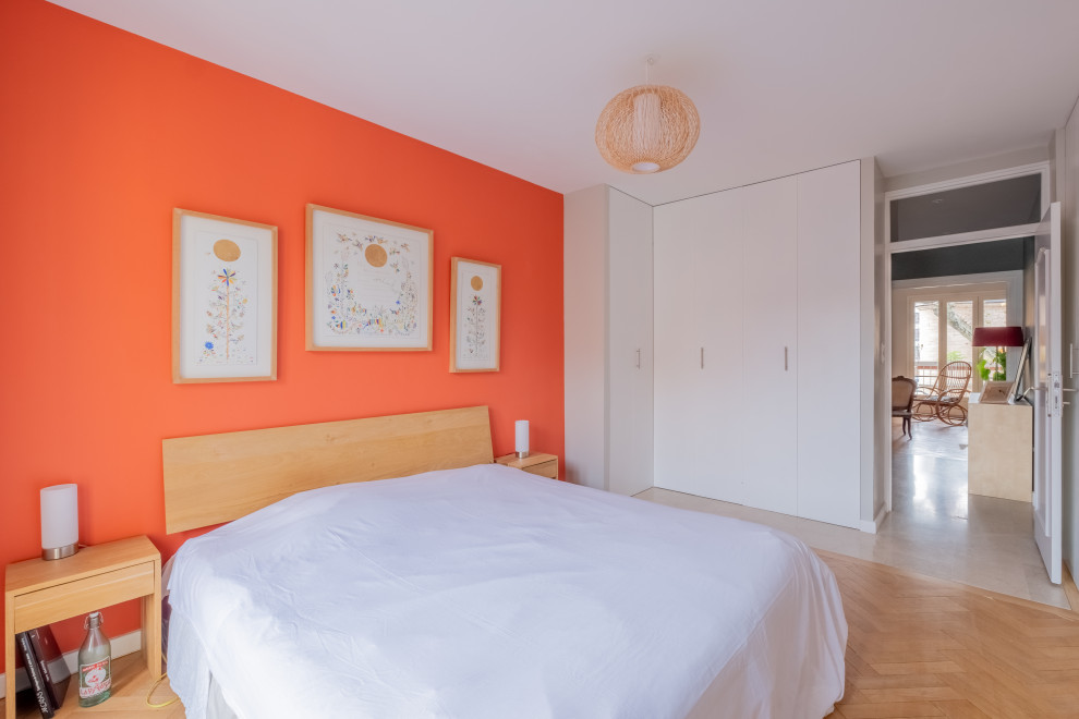 Foto de dormitorio principal bohemio de tamaño medio con paredes rojas y suelo de madera clara