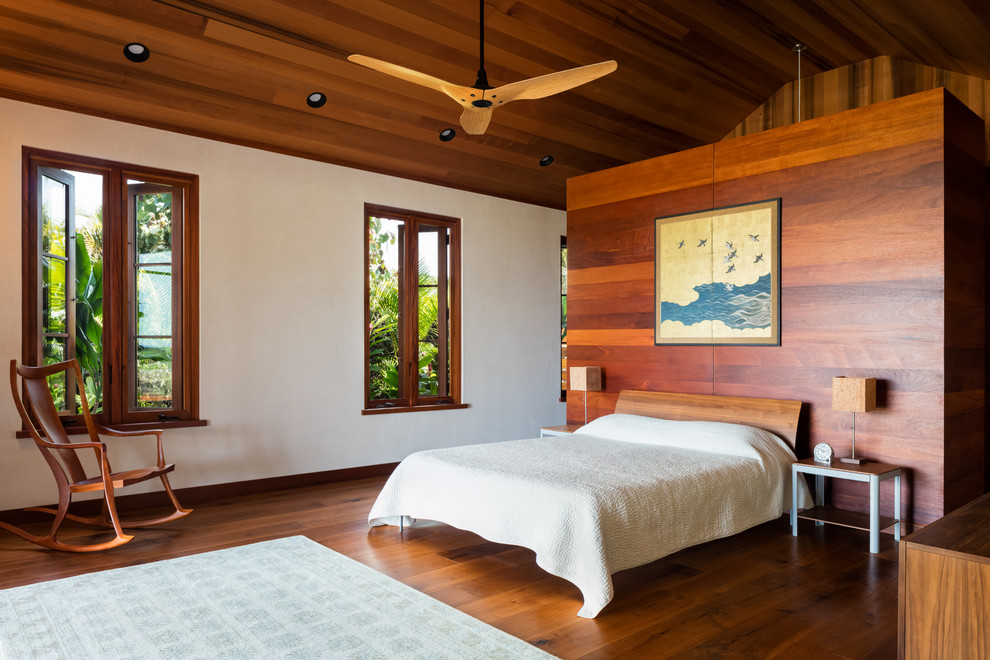 Photo of a tropical bedroom in Hawaii with white walls, dark hardwood floors and brown floor.