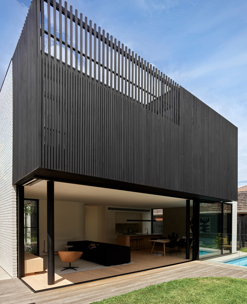 Immagine della villa nera moderna a due piani di medie dimensioni con rivestimento in legno, tetto piano e copertura in metallo o lamiera