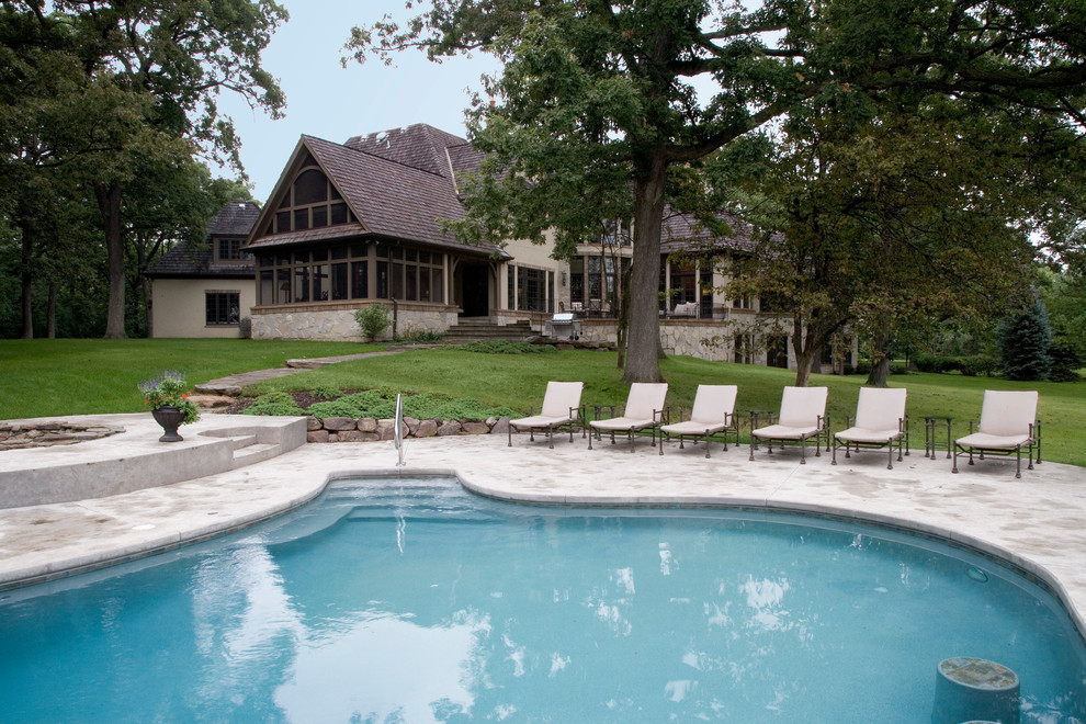 This is an example of an expansive traditional backyard custom-shaped pool in Chicago with concrete slab.